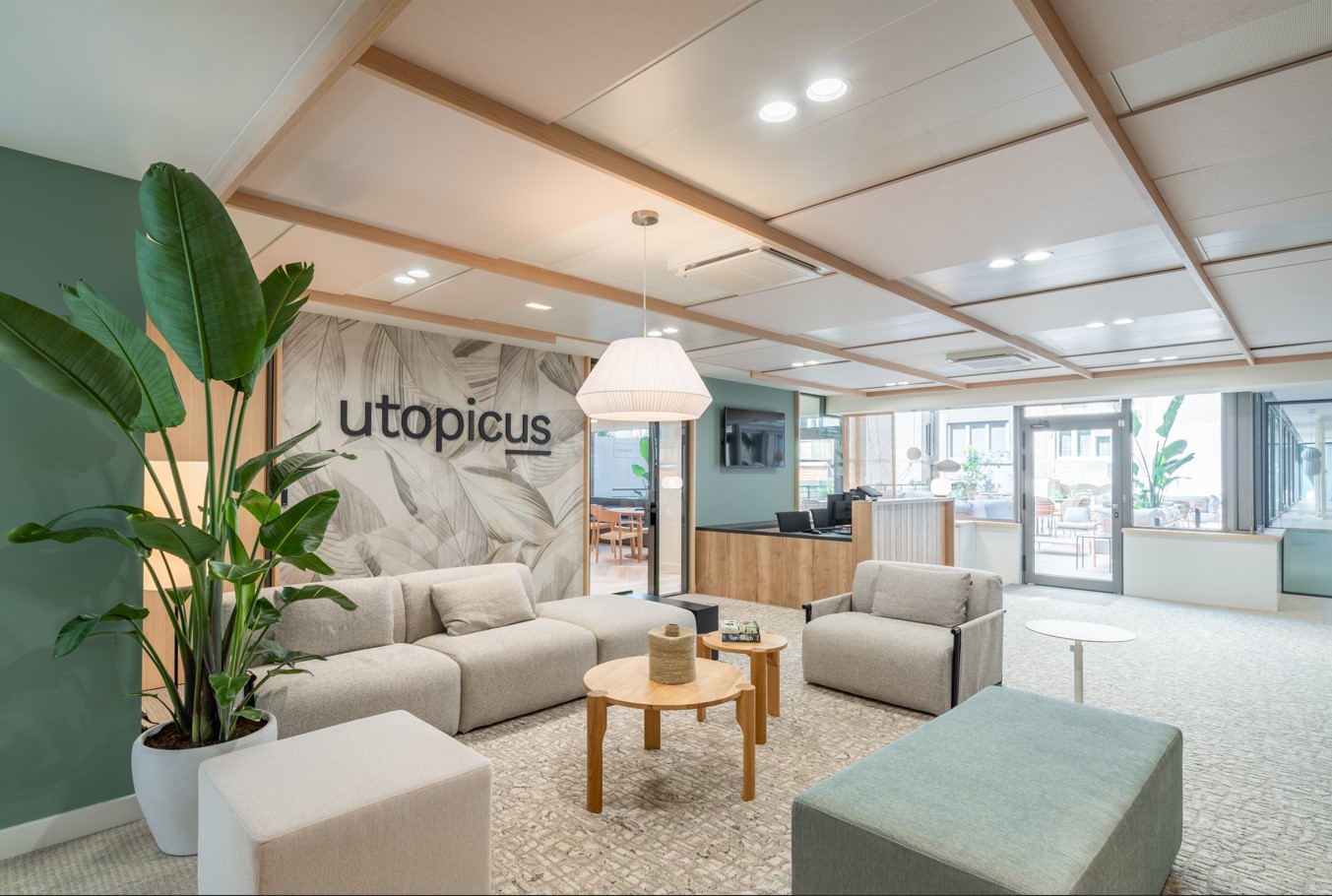 Entrada de una oficina con mucha luz, sillones y plantas